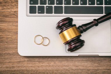 Boşanma kavramı. Alyans ve yargıç tokmak bilgisayar dizüstü, ahşap arka plan, üstten görünüm