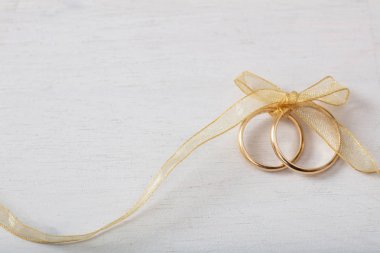 Bir çift altın alyans Beyaz ahşap arka plan, kopya alanı üzerinde altın bir şerit ile bağlı