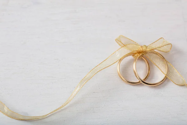 Pair Golden Wedding Rings Tied Golden Ribbon White Wooden Background — Stock Photo, Image