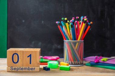 Okula dönüş. 1 Eylül tarihi ve renkli okul malzemeleri tahta arka plan üzerinde