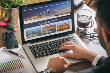 Uçuşlar online rezervasyon ve rezervasyon. Bir bilgisayar ekranında, office iş geçmişi Arama uçuşlar ile çalışan adam.