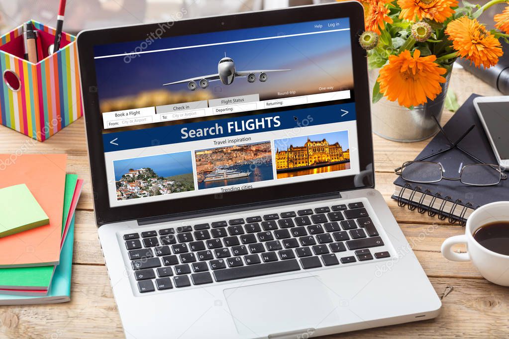 Flights online booking and reservation. Search flights on a computer laptop screen, office desk background.