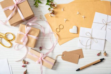 Düğün hazırlığı. Hediyeler ve düğün davetiyeleri bir beyaz tahta masa, arka plan üzerinde düz lay ve en iyi görünümü.