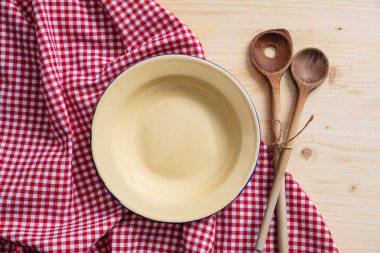 Rustik yer ayarı. Boş levha, mutfak gereçleri ve ahşap masa, üstten görünüm, üzerinde kırmızı masa örtüsü uzay kopyalayın