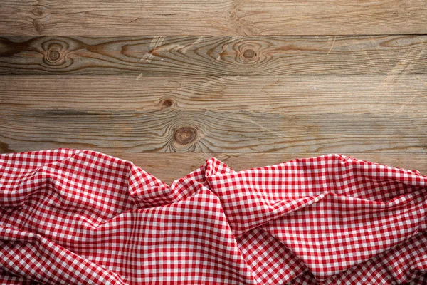 Red and white checkered picnic tablecloth on wooden background, copy space
