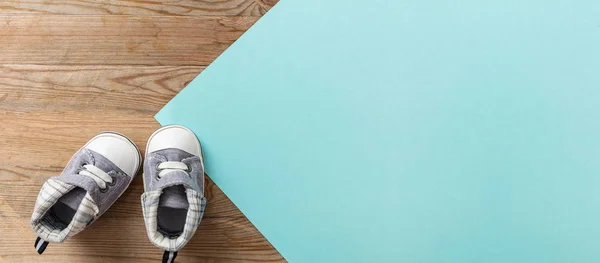 Baby boy shoes, shower invitation concept, on pastel blue and wooden background, banner, copy space, top view