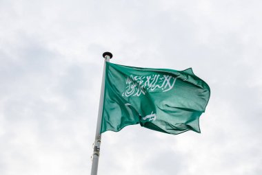 Suudi Arabistan bayrağı. Bir kutup sallayarak, bulutlu gökyüzü arka plan üzerinde Suudi Arabistan bayrağı