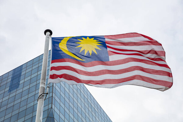 Malaysia flag. Malaysian flag on a pole waving, modern office building background