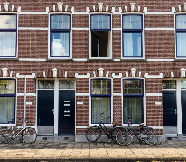 Rotterdam, Netherlands. Bicycles in front of traditional red brick houses with blue windows background.