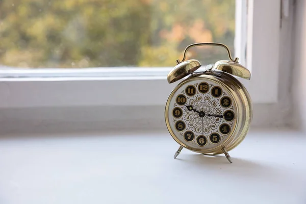 Time management. Golden alarm clock in the morning, blur glass window background,