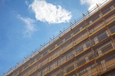 Under construction. Building construction with scaffolding, blue sky background clipart
