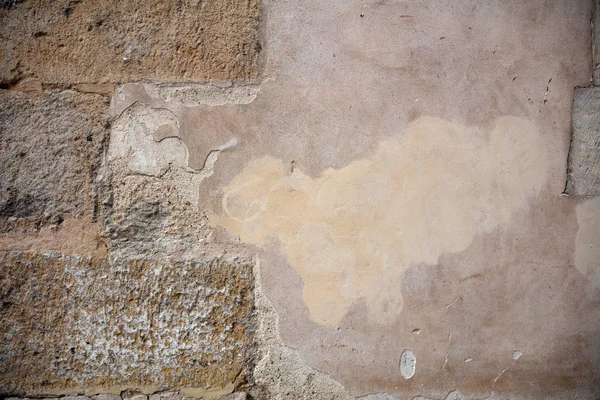 Faded plastered and stone masonry wall, texture grunge background.