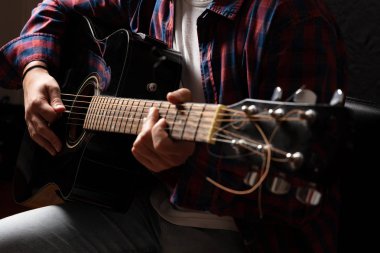 Genç adam gitar, görünümü, koyu arka plan kadar yakın