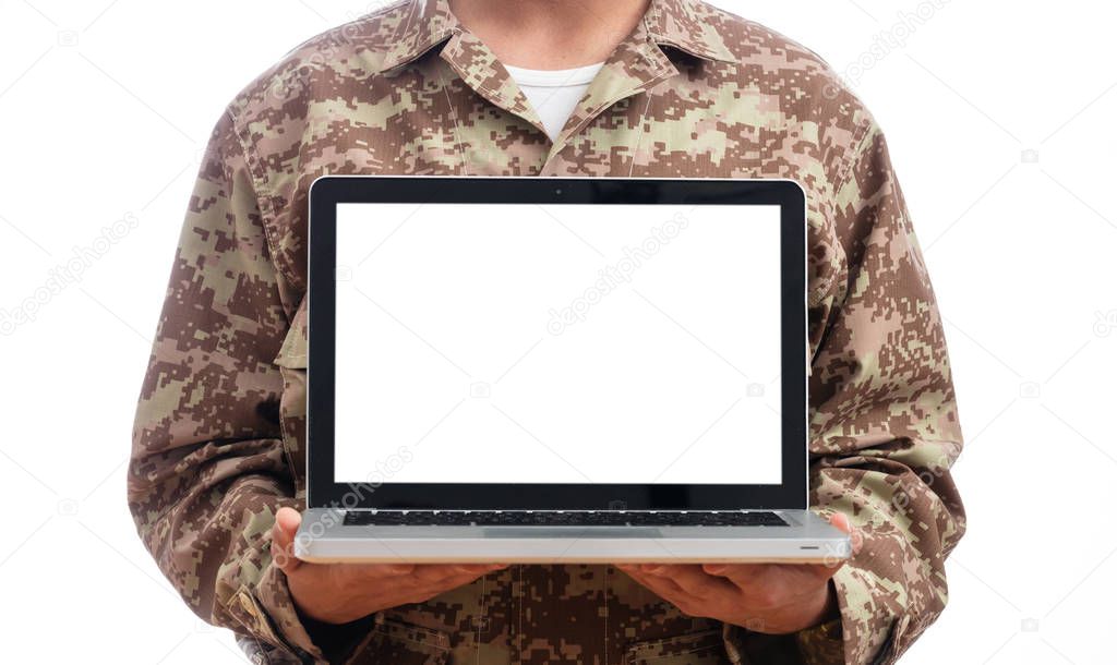 US Army. Young soldier showing a laptop computer with blank screen on white background