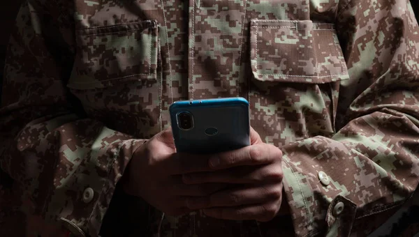 私たちの軍隊 暗い背景に携帯電話の地位を保持している若い兵士 — ストック写真