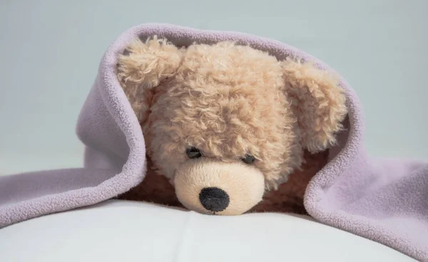 Kids bedtime, baby shower. Cute teddy laying on bed mattress covered with a towel