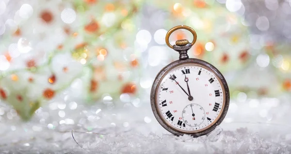 New Years eve countdown. Minutes to midnight on an old pocket watch, bokeh background, copy space