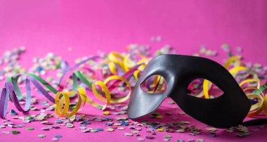 Karnaval parti. Siyah maske, flamalar ve konfeti parlak pembe arka plan üzerinde afiş