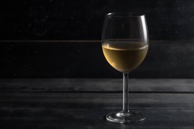 Şarap tadımı. Kristal cam kopya alanı, ahşap koyu arka plan üzerinde beyaz şarap ile ön görünüm