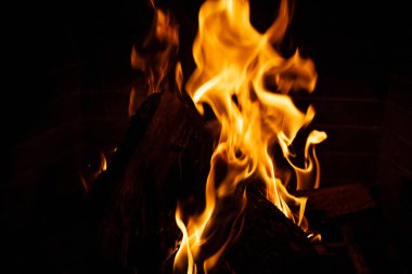 Sıcak şömine. Ahşap günlükleri yanma, koyu arka plan, gevşeme ve sıcak ev, closeup detayları ile göster