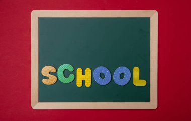 Okul kavramı. Ahşap çerçeve, kelime, metin okul renkli harfler, kırmızı duvar arka plan, kopya alanı ile yeşil yazı tahtası
