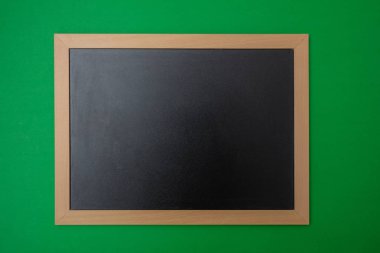Siyah boş boş yazı tahtası ahşap çerçeve, yeşil duvar arka plan ile. Metin için yer