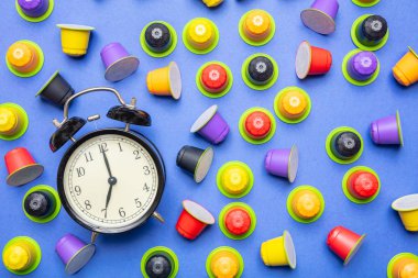 Kahve zamanı. Çalar saat ve espresso kapsül, bakla Eko Dostu, mavi renk arka planda, üstten görünüm compostable