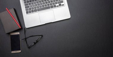 Modern çalışma alanı. Bilgisayar dizüstü bilgisayar ve cep telefonu siyah ofis masasında, üstten görünüm alanı Kopyala