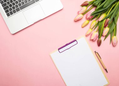 Bayan, anneler günü kavramı. Pembe lale buketi, boş not defteri ve pastel pembe, üstten görünüm, bilgisayar laptop alanı Kopyala