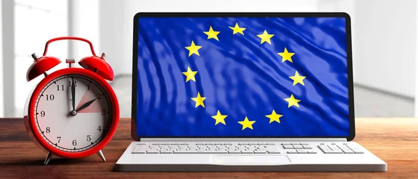 European daylight saving time end. Red alarm clock and eu flag on a laptop screen on wooden desk, banner. 3d illustration