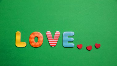 Renkli harfler ve yeşil renk arka plan üzerinde küçük kırmızı kalpler aşk metin