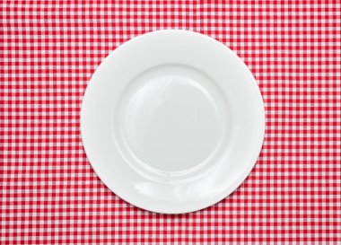 Kırmızı kareli masa örtüsü arka plan, üstten görünüm, kopya alanı boş beyaz tabakta