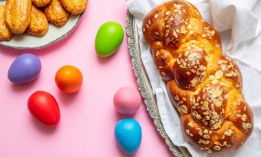 Paskalya yumurtaları ve çörek örgü, pembe renkli arka plan üzerinde Yunan Paskalya tatlı ekmek