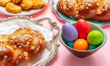 Paskalya yumurtaları ve çörek örgü, pembe renkli arka plan üzerinde Yunan Paskalya tatlı ekmek