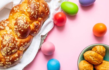 Paskalya yumurtaları ve çörek örgü, pembe renkli arka plan üzerinde Yunan Paskalya tatlı ekmek