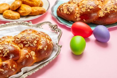 Paskalya yumurtaları ve çörek örgü, pembe renkli arka plan üzerinde Yunan Paskalya tatlı ekmek