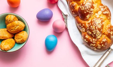 Paskalya yumurtaları ve çörek örgü, pembe renkli arka plan üzerinde Yunan Paskalya tatlı ekmek