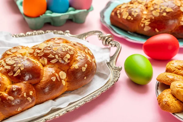 Easter eggs and tsoureki braid, greek easter sweet bread, on pink color background — Stock Photo, Image