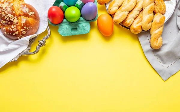 Huevos de Pascua y trenza tsoureki, pan dulce griego de Pascua, sobre fondo amarillo — Foto de Stock