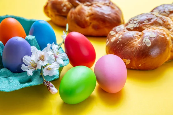 Huevos de Pascua y trenza tsoureki, pan dulce griego de Pascua, sobre fondo amarillo — Foto de Stock