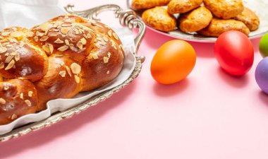 Paskalya yumurtaları ve çörek örgü, pembe renkli arka plan üzerinde Yunan Paskalya tatlı ekmek