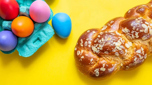 Huevos de Pascua y trenza tsoureki, pan dulce griego de Pascua, sobre fondo de color amarillo — Foto de Stock