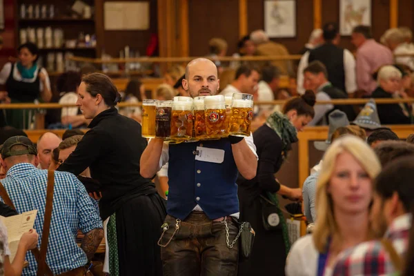 Munich, Germany, Oktoberfest, Waiter holding beers, tent interior background