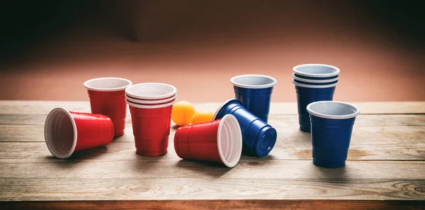 Пивний понг. Пластикові червоно-сині кольорові чашки та кульки для пінг-понг на дереві, банер — стокове фото