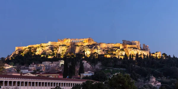 Acrópolis de Atenas Grecia roca y Partenón iluminado, cielo azul fondo tarde en la noche . — Foto de Stock