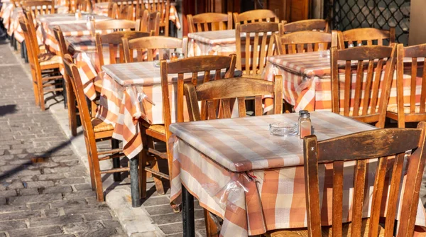 Griechische Taverne im Freien, leere Tische und Stühle, sonniger Tag, Stadtzentrum — Stockfoto