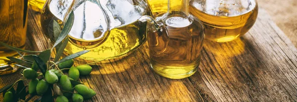 Huile d'olive en bouteilles de verre sur table en bois, bannière, vue rapprochée — Photo