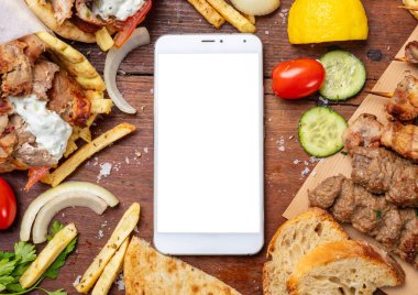 Gyro pide, shawarma, online sipariş. Et ve ahşap masa boş ekran cep telefonu ile iki tamamladı