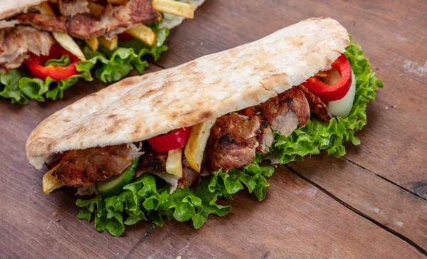 Gyros, shawarma, take away, street food.  Sandwich with meat on wooden table