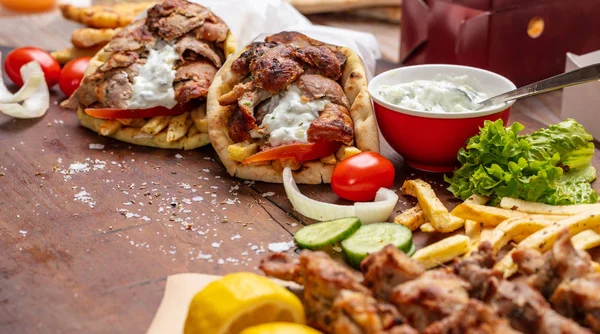 Gyro pita, shawarma, souvlaki. Två pita bröd wraps och kött spett på träbord — Stockfoto